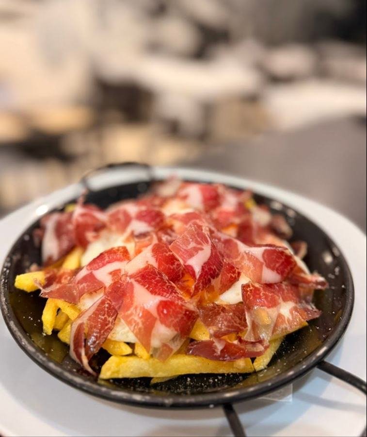 Huevos rotos con patatas y jamón en sartén