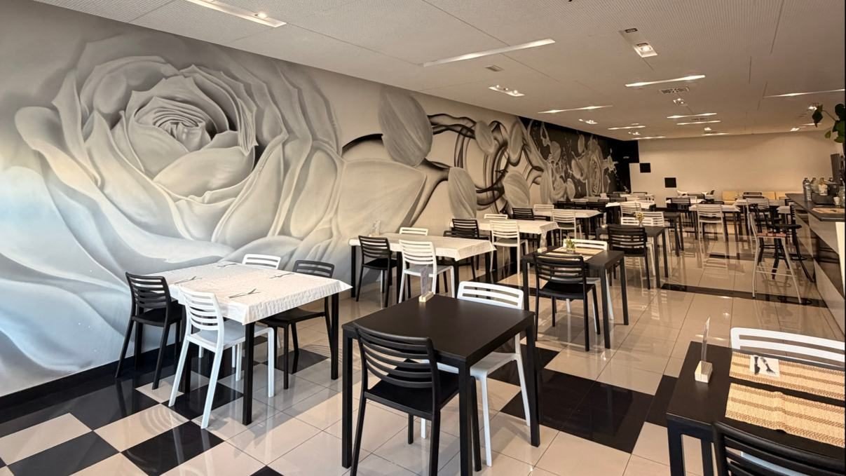 Comedor de Blanc i Negre Badalona con un gran mural de una rosa en blanc i negre y suelo ajedrezado