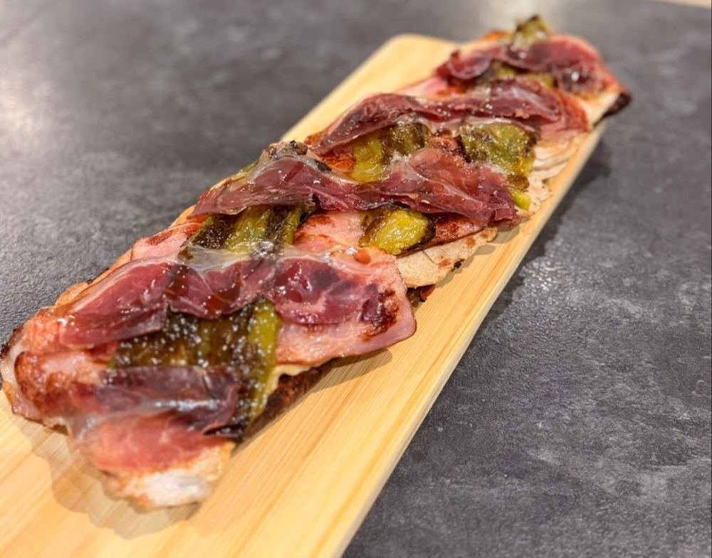 Torrada sobre tabla de madera con jamón y pimientos